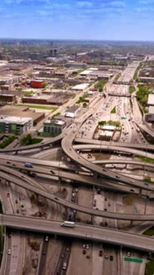 Road loops and junctions with multiple automobiles moving along. Low architecture of Chicago city.
