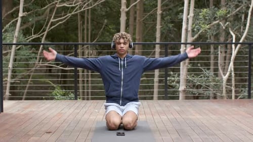 Young Adult Meditating on Outdoor Deck