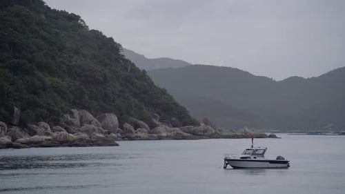 A Fishing Boat Bobs on the Waves Against a Backdrop of a Mountain in the Bay