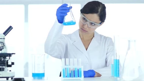 Woman Scientist Analyzes Blue Liquid in Lab