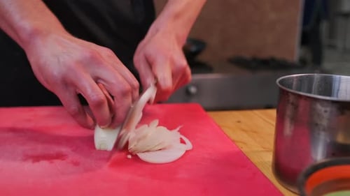 Chef Slices Onion on Cutting Board with Cleaver