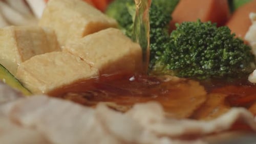 Gros plan d'une soupe versée sur du shabu, des ingrédients qui tournent dans la cuisine