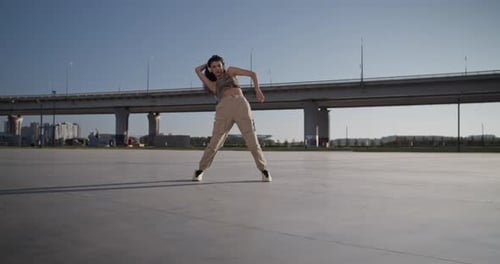 Young Woman Dancing Against Bridge in Morning