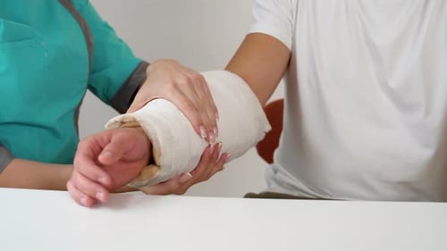 Doctor Examining Patient's Arm with Cast in Hospital