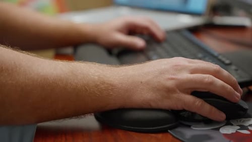 Hände, die am Arbeitsplatz tippen und die Maus benutzen