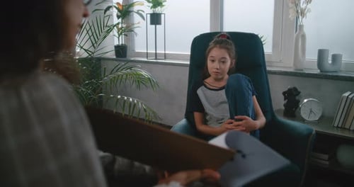 Kinderpsychologin zeigt einem asiatischen Mädchen im Schulalter Bilder und führt einen psychologischen Test durch