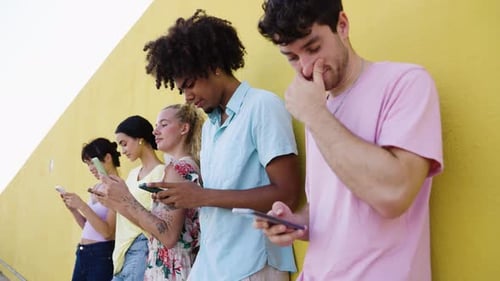 Young Adults Standing Near a Wall Using Phones