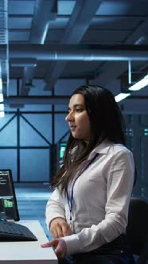 Vertical Video Engineer in Data Center Sitting Down at Desk Installing Software