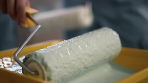 Closeup View of Paint Roller with White Color on It in Man