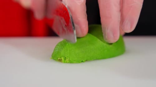 Gloved Hands Slicing Fresh Avocado on Cutting Board