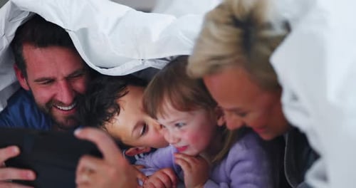 Happy Family Enjoying Tablet Under Blanket Indoors