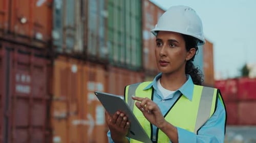 Woman Walks Through An Outdoor Warehouse Holding Clipboard Talking And Checking Inventory List