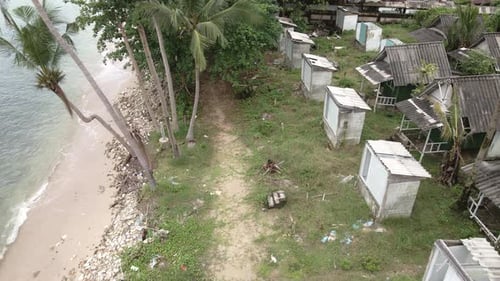 aerial birds eye view dolly shot of a abandoned derelict destroyed beach bungalow resort on the beac