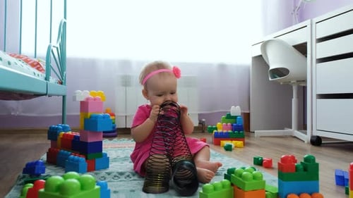 Baby Girl Playing with Spring and Blocks at Home