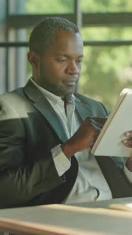 Man in Business Suit Uses Tablet in Office