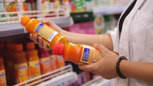 Young Woman Choosing Juices in the Supermarket