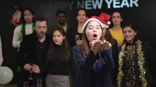 Festa de Ano Novo, grupo de jovens com chapéus de Papai Noel soprando confetes enquanto comemoram o ano novo