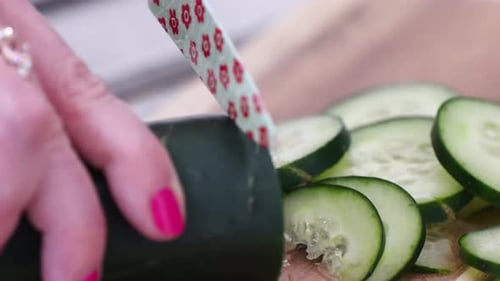 Female Chef Chopping Cucumber into Thin Slices Close Up on Wooden Cutting Board with Small Knife Dec
