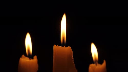 Burning Candles Illuminate Dark Background in Close Up