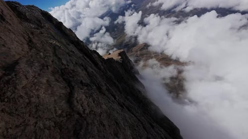 Wispy Clouds Gliding Over Rugged Mountain Ridgeline Exposing Raw Geological Terrain Through