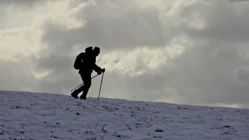 Backpacker Silhouette Walking on Snow Covered Hill