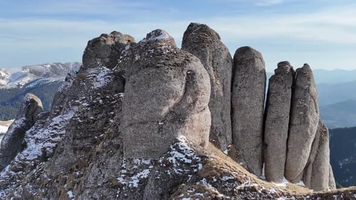 Las escarpadas cumbres de las montañas de Ciucas bajo un cielo azul claro, parches de nieve que se adhieren a las rocas