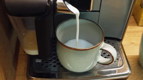 Steaming Milk Pouring into Mug from Coffee Machine