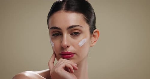 Woman, beauty and face with moisturizer for skincare or facial treatment on studio background