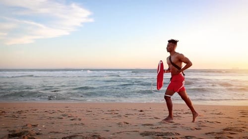 Male lifeguard running along the beach
