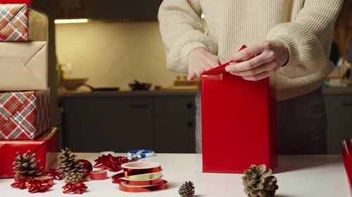 Woman Wrapping Christmas Gift with Red Paper