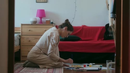 Woman Painting with Watercolors on Floor at Home