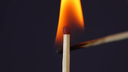 Hand igniting matches close up macro shot captured in front of black background in slow motion at 12