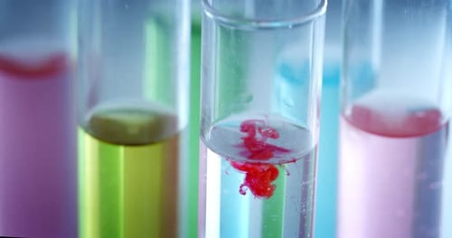 Une macro au ralenti de molécules de microparticules dans un liquide coloré dans des tubes est analysée pour déterminer la résolution