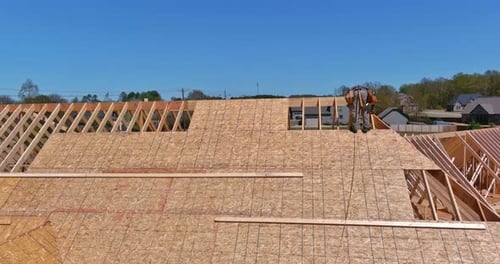 Carpentry Construction Works Workers Hammering Nail Into Plywood on Roof Top of Future House