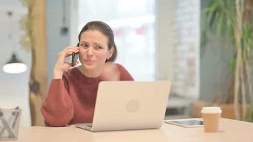 Woman Talking on Phone With Laptop in Office