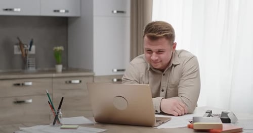 Blond Man Using Laptop for Video Call at Home