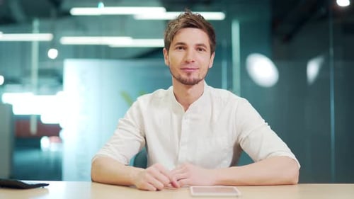 Professional Young Man Sits at Desk in Office