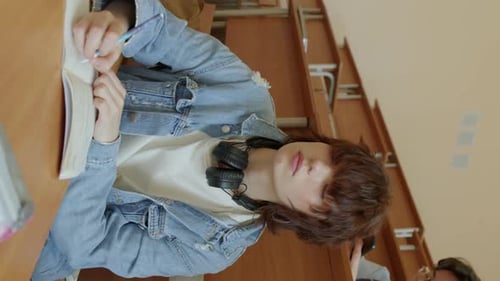 Student Writing in a Notebook in a Classroom