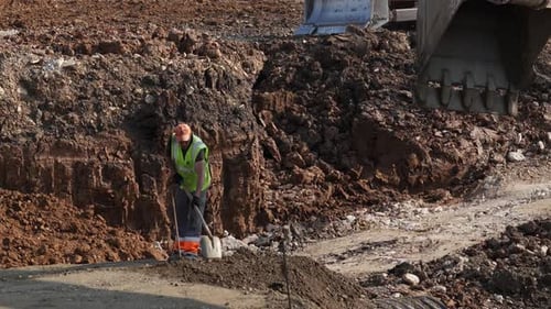 Construction Worker Shoveling Dirt at Building Site Clip