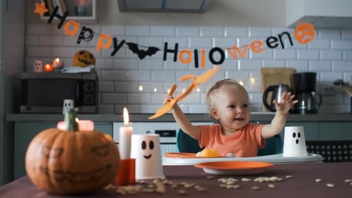 Infant Plays with Halloween Costume in Decorated Kitchen