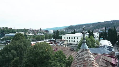 Flying over a church in old city of Tbilisi overlooking kura river