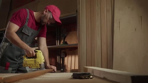 A Skilled Craftsman is Focused on His Woodworking Project Using a Electric Jigsaw to Cut Timber