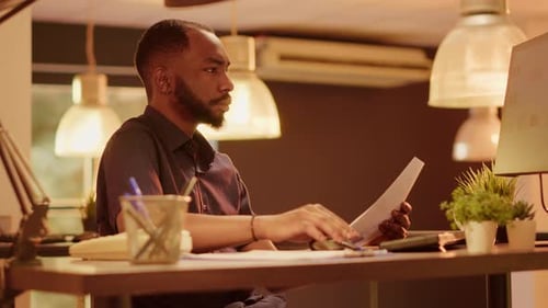 Man Reviews Documents At Desk in Workplace