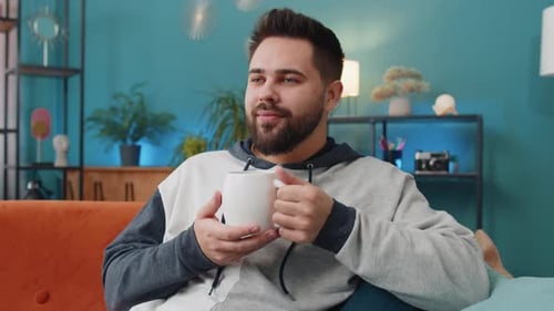 Man Drinking Beverage and Relaxing on Couch