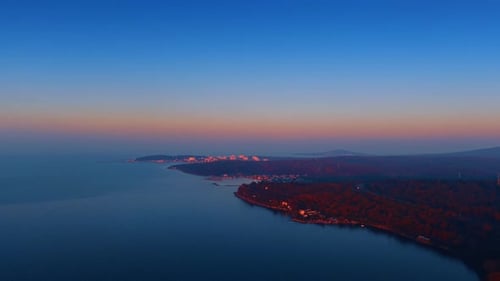 Footage over the tranquil blue waterscape at the wooded coast.