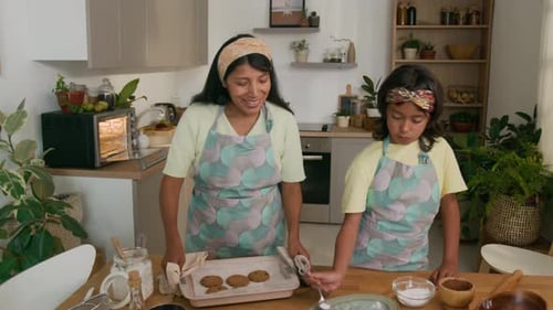 Woman and Child Baking Cookies Together in Kitchen