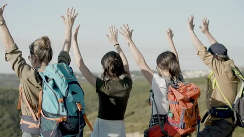 Back View of Family Standing on Mountain Top Raising Arms