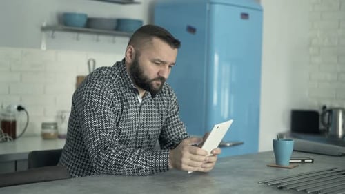 Man Using Tablet in Kitchen with Blue Refrigerator