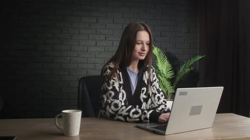 Smiling Female Freelancer is Typing Fast on Her Laptop A Brunette Woman Works with Computer at Home