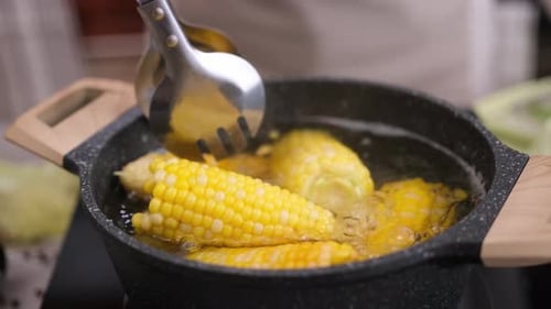 Bright Corn Boiling in Pot with Tongs
